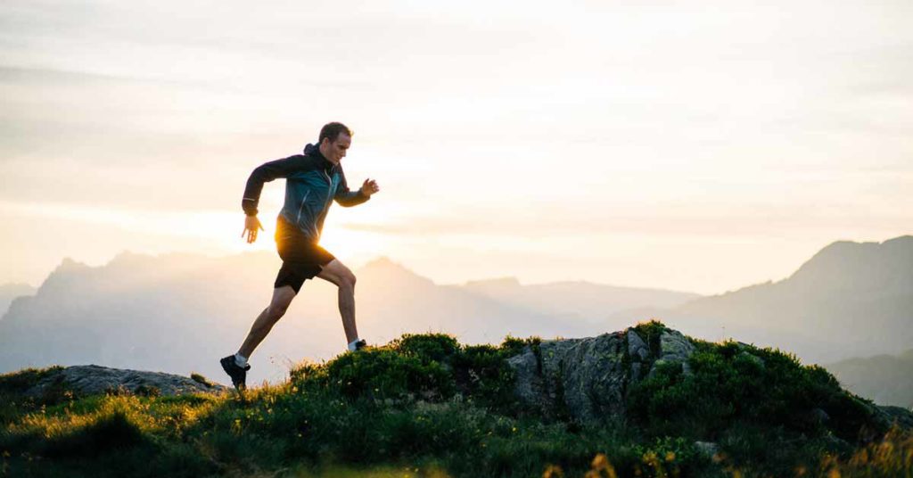 runner cresting mountain at sunrise