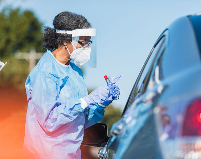 medical worker administers covid test to driver of vehicle