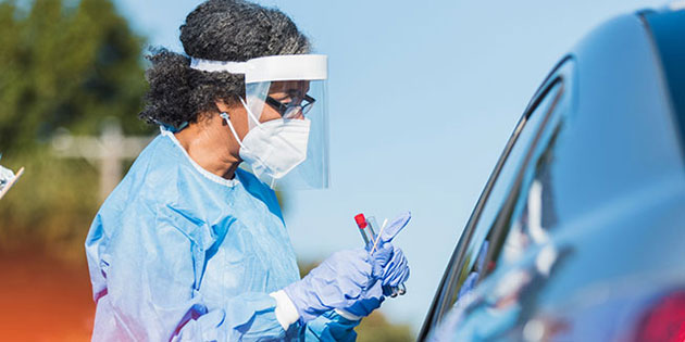 medical worker administering a covid test to someone in a car