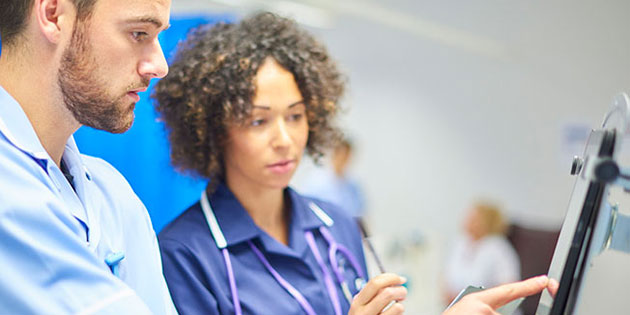 two medical workers consult a screen