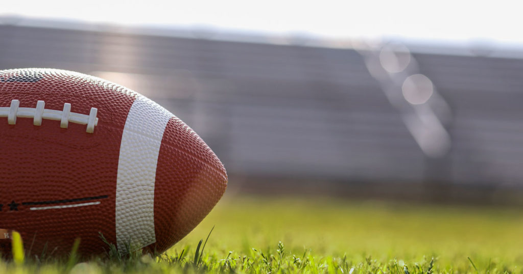 football resting on the grass of a stadium