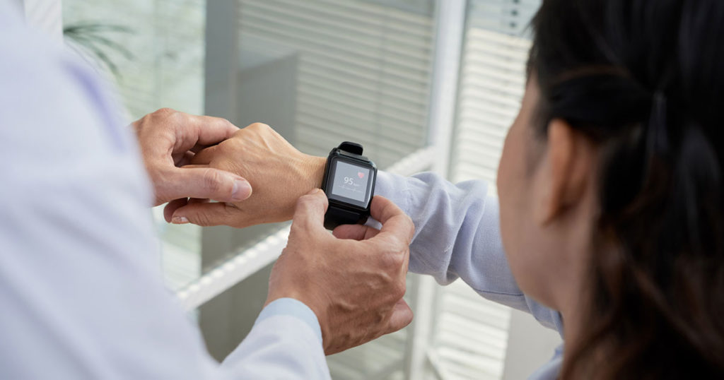 doctor checks patient's health monitor worn on wrist