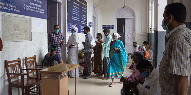 people stand in line at a clinic in India
