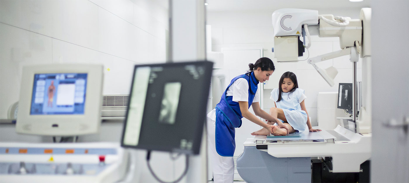 medical technician guides a young patient on a table