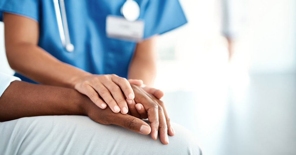 healthcare worker holding patient's hand