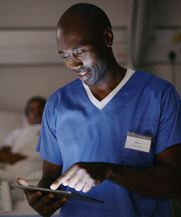 registered nurse consults digital tablet by patient's bedside