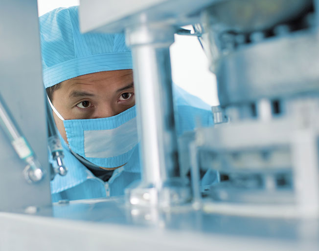 masked employee inspects machinery