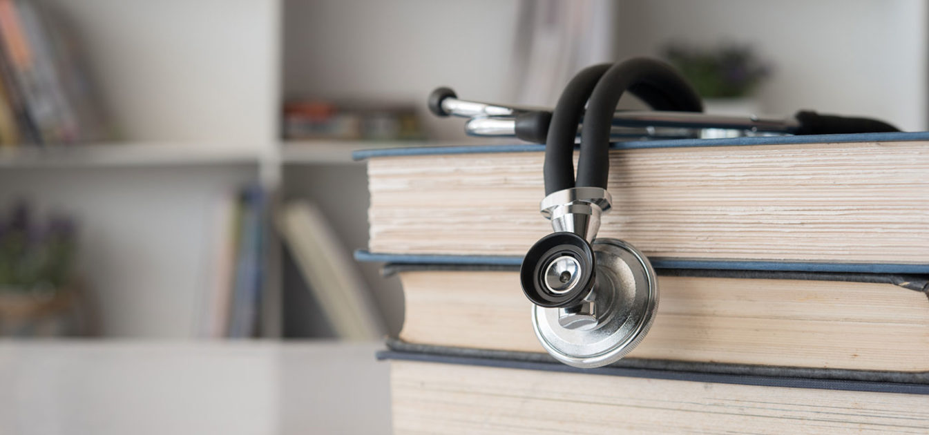 stack of books with stethoscope in library