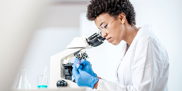 scientist looks through glasses into microscope