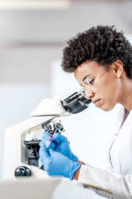 scientist looks through glasses into microscope
