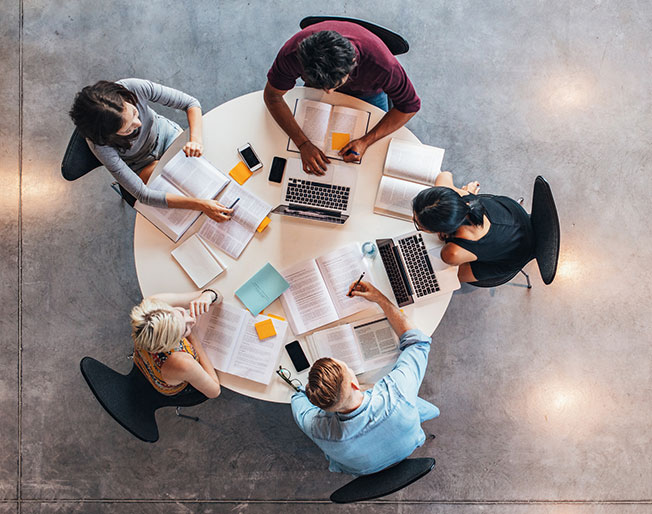 five people seated around a table planning