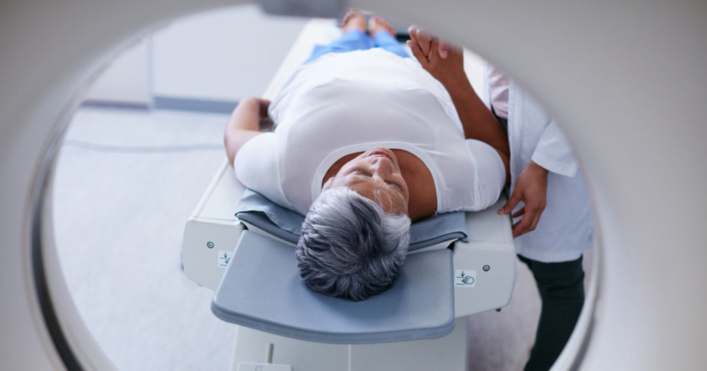 senior woman being comforted by doctor before an MRI scan