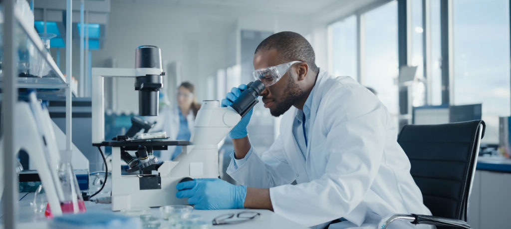 medical researcher in lab looks into microscope