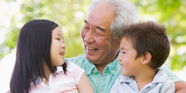 smiling grandfather holds two grandchildren outside