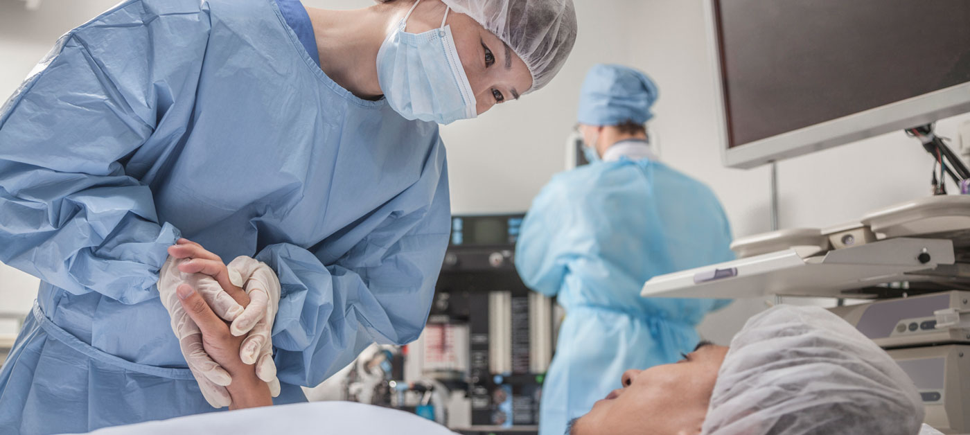 surgeon holds patient's hand in operating room