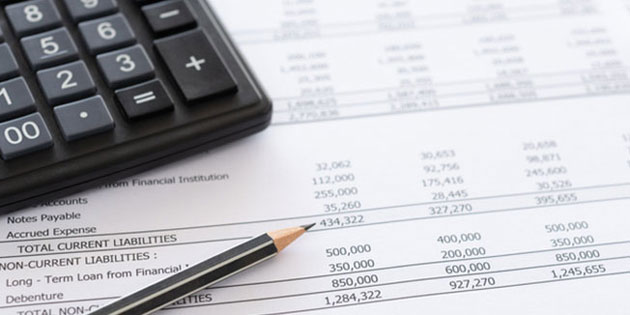 calculator and pencil on spreadsheet of figures