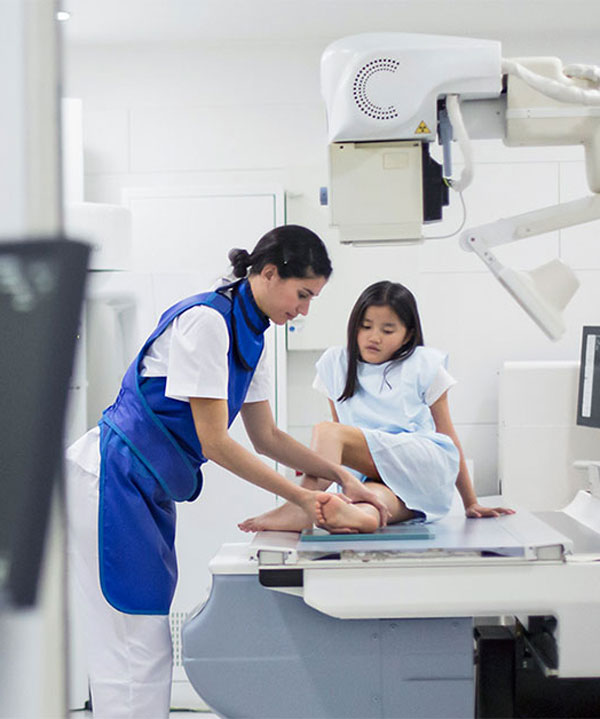 diagnostic technician positions child's leg for scan