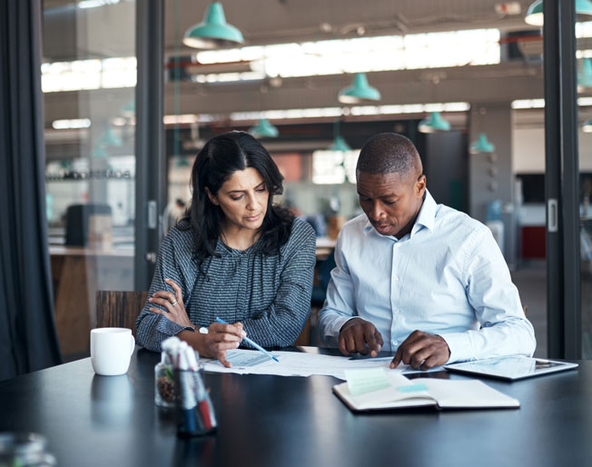 two colleagues review paperwork in a meeting room