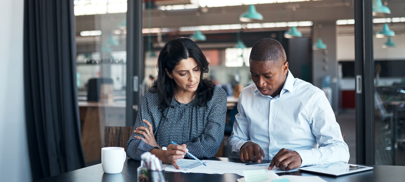 two colleagues review paperwork in a meeting room