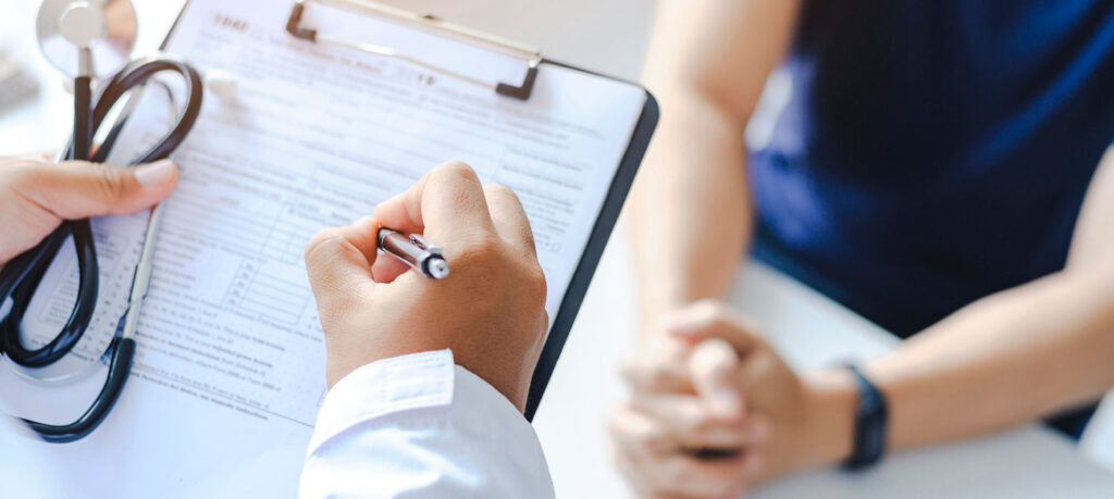 doctor writes on clipboard by patient