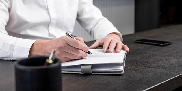 someone writing in a notebook at a desk