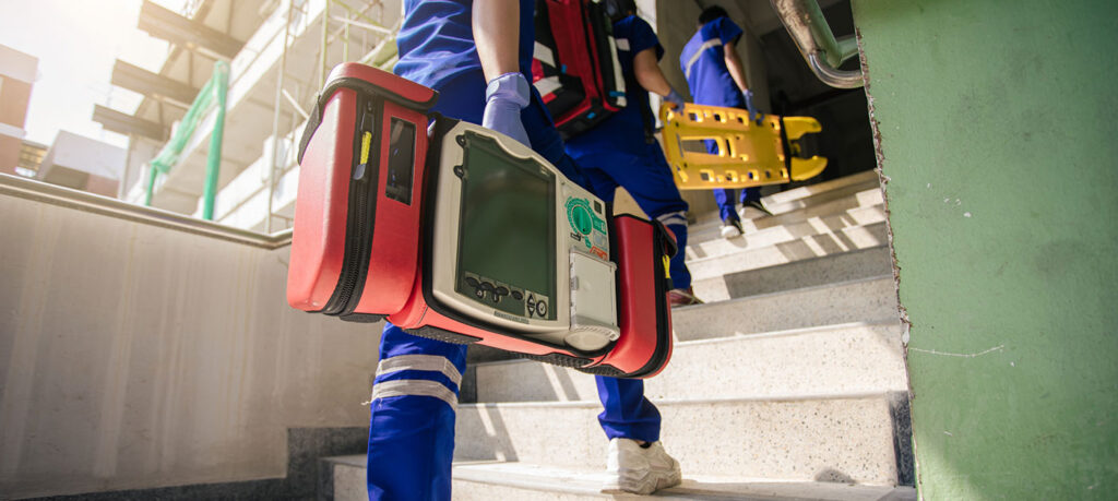 two emergency responders walking up stairs, one carrying an automatic external defibrillator or AED
