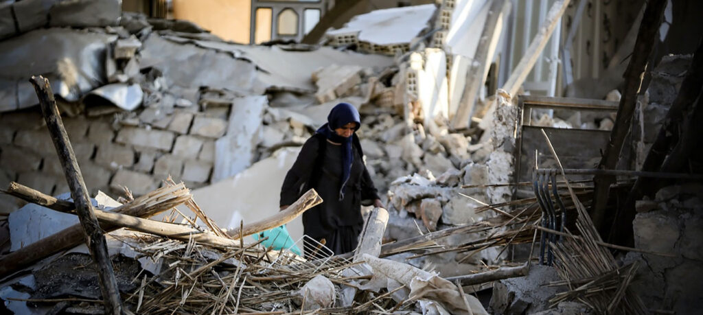 person walks amongst the rubble of an earthquake