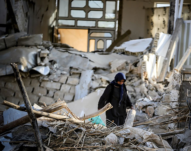 person walks amongst the rubble of an earthquake
