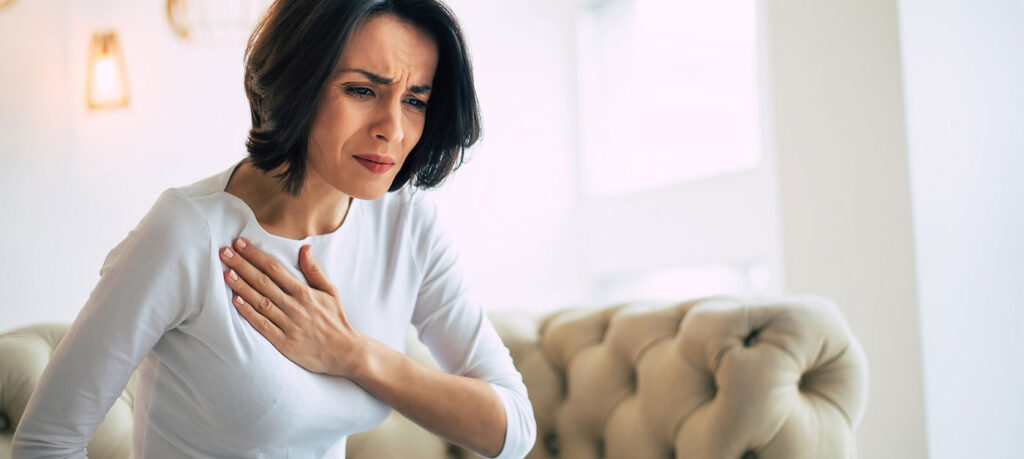 woman grimacing and holding chest