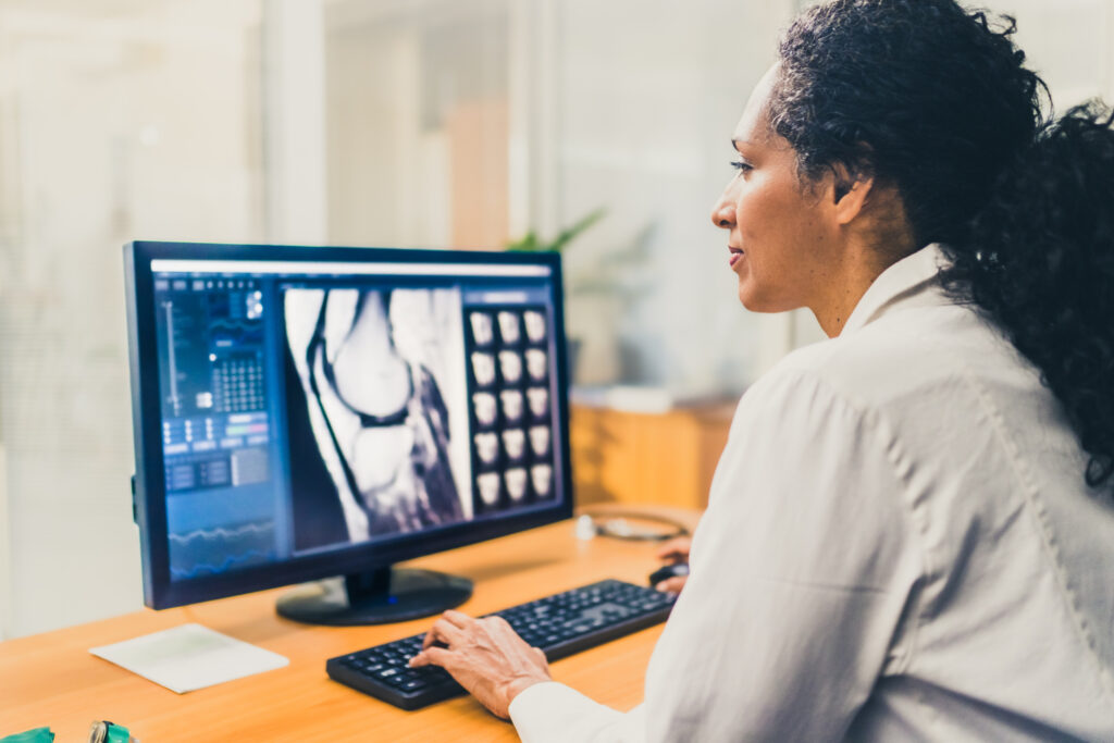 woman in a lab coat looking at xray scan on a computer screen